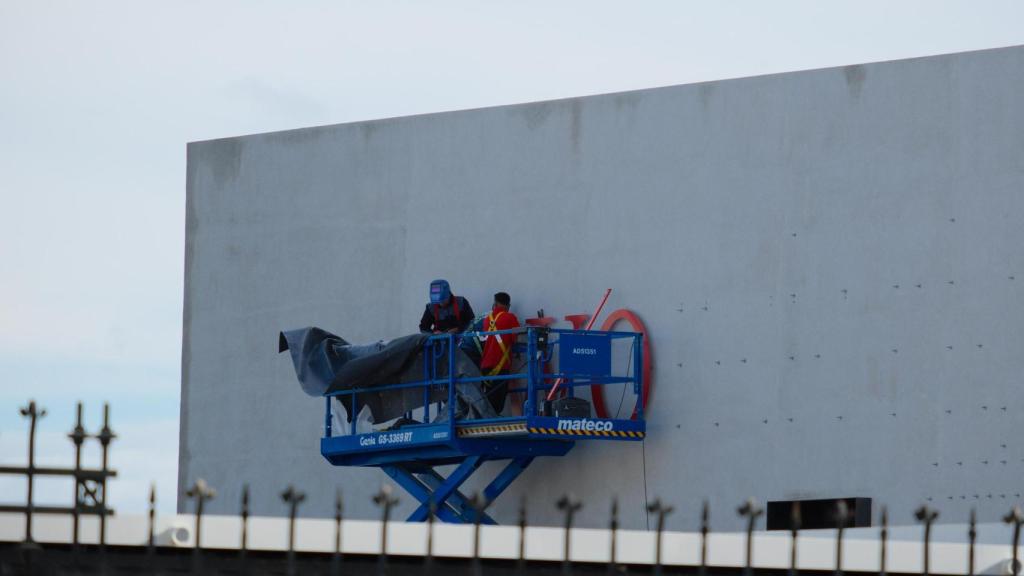 Operarios instalando el nuevo letrero de la próxima exposición de la Fundación MOP