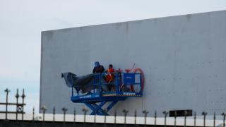 Operarios instalando el nuevo letrero de la próxima exposición de la Fundación MOP