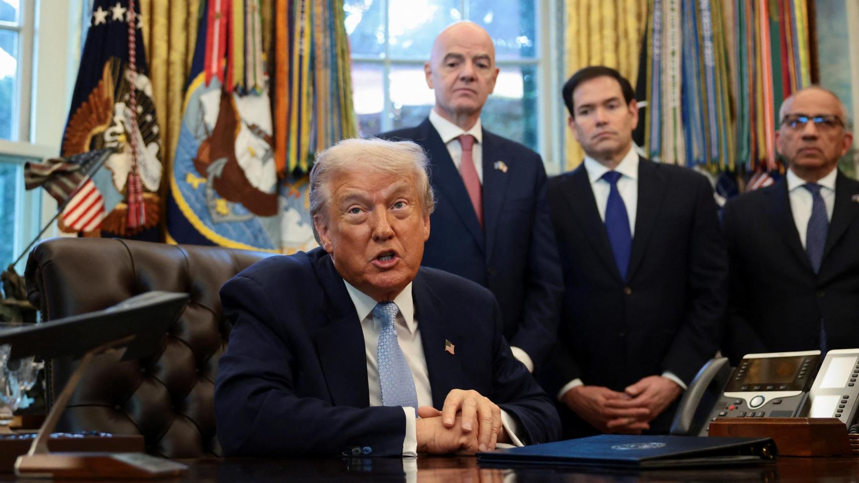 Trump, compareciendo en el Despacho Oval mientras Infantino le observa a su espalda