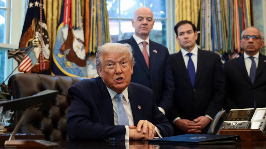 Trump, compareciendo en el Despacho Oval mientras Infantino le observa a su espalda