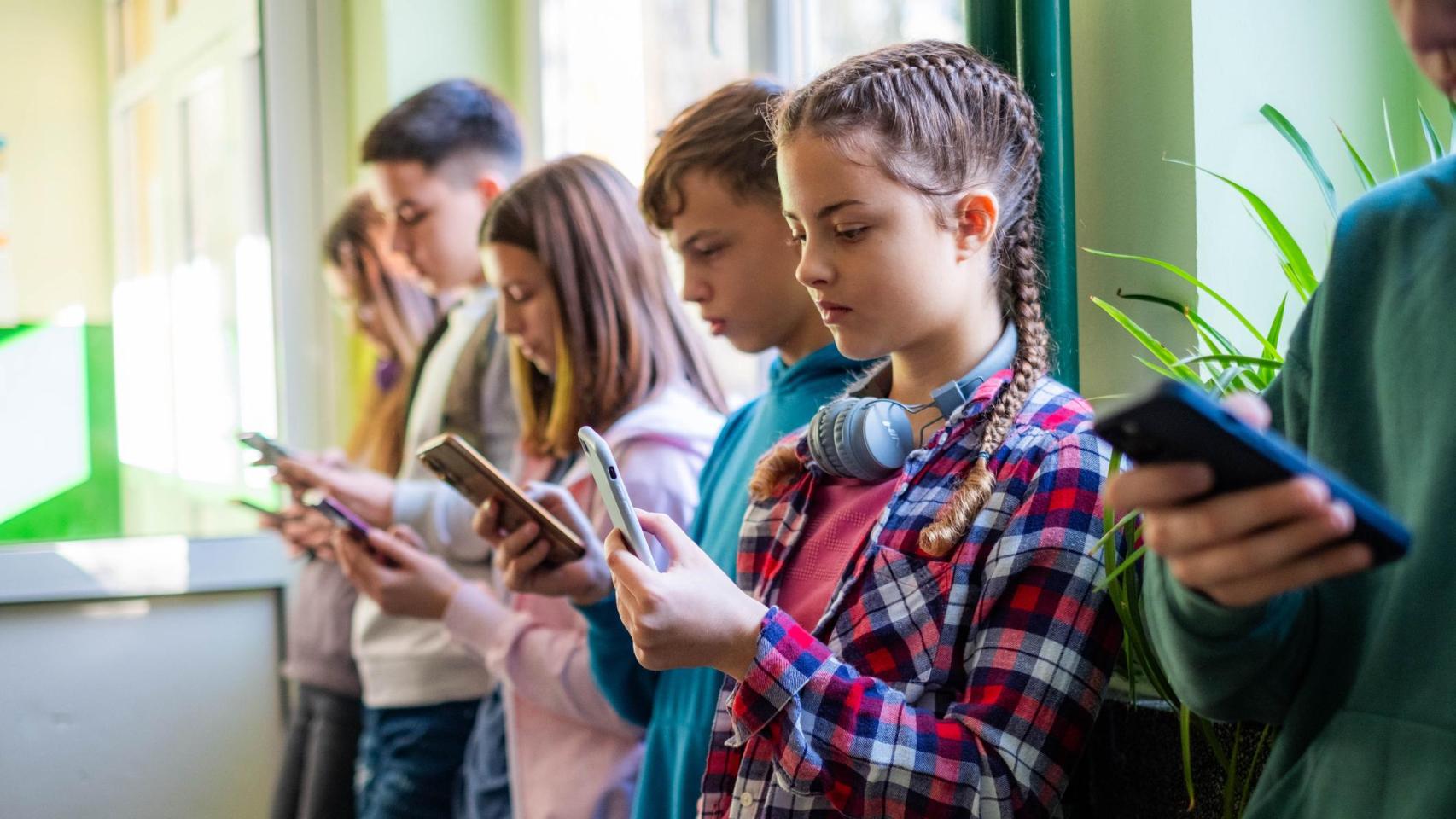 Un grupo de jóvenes mirando sus teléfonos móviles.