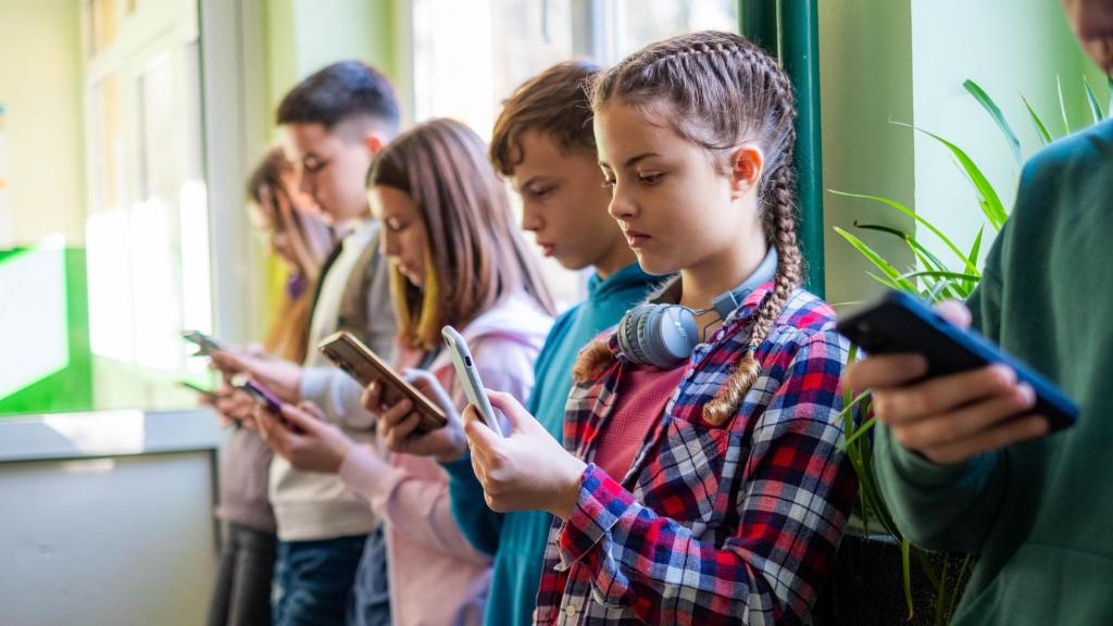 Un grupo de jóvenes mirando sus teléfonos móviles.