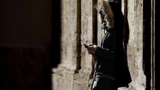 Imagen de archivo de una persona joven mirando su móvil en la calle.