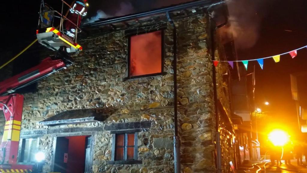 Los bomberos tratan de sofocar las llamas para evitar que se propague a la vivienda anexa