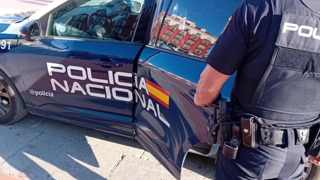A member of the National Police, next to a patrol car, on a street in Valladolid.