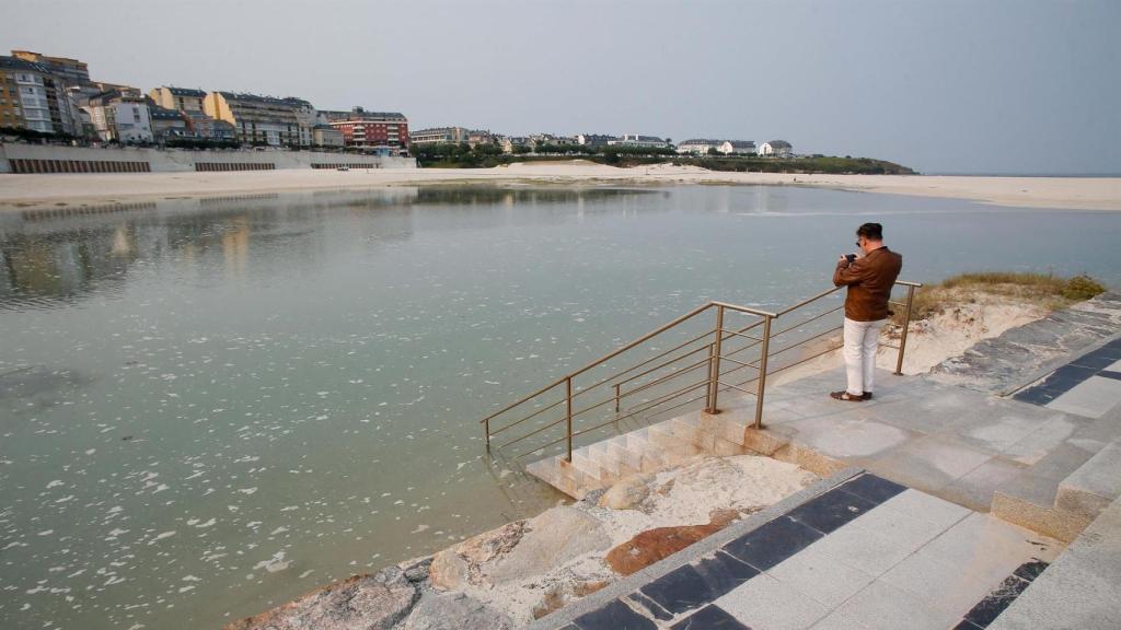 Una persona fotografía la pleamar en el espigón de Foz, junto a la playa de A Rapadoira.