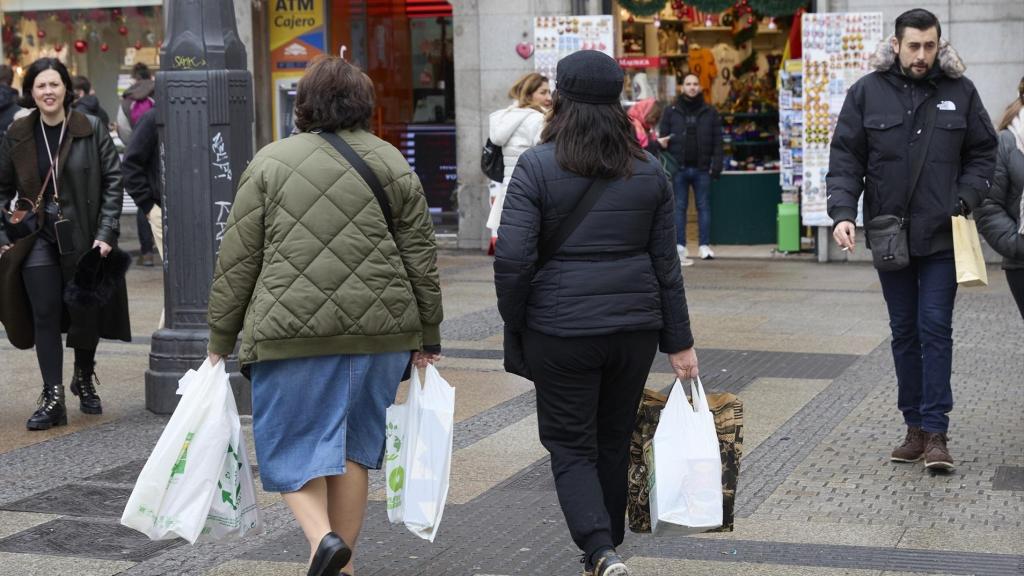 Dos mujeres pasean con bolsas de la compra.