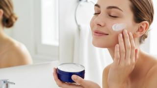 Mujer aplicándose crema Nivea en el rostro.