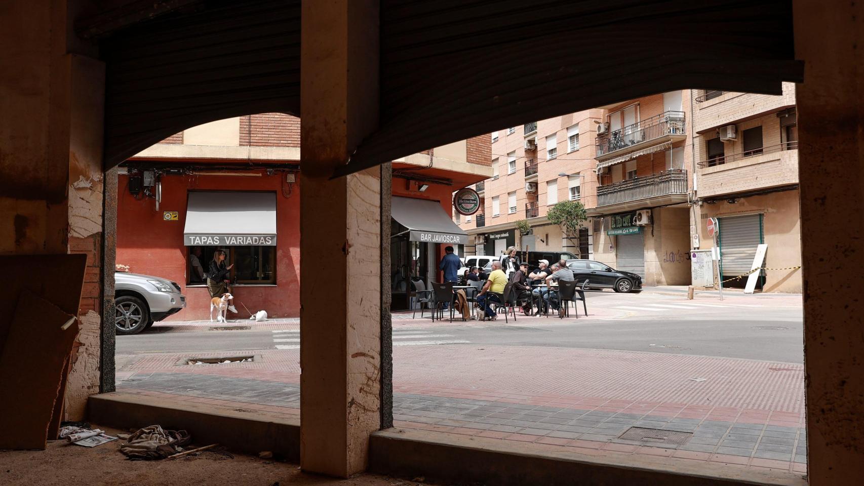 Varias personas toman algo en la terraza de un bar en Catarroja, ante un bajo afectado. Efe / Manuel Bruque