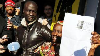 Ngagne y su esposa con el boleto ganador de el Gordo de la Lotería de Navidad.