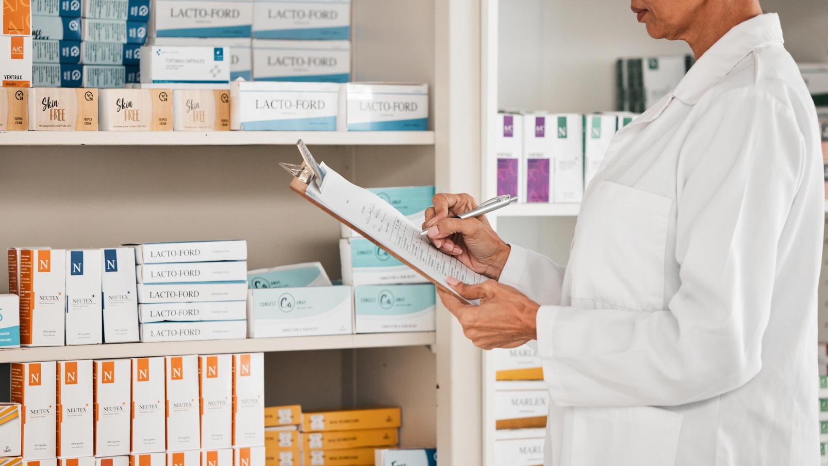 Mujer farmacéutica frente al stand de medicamentos.