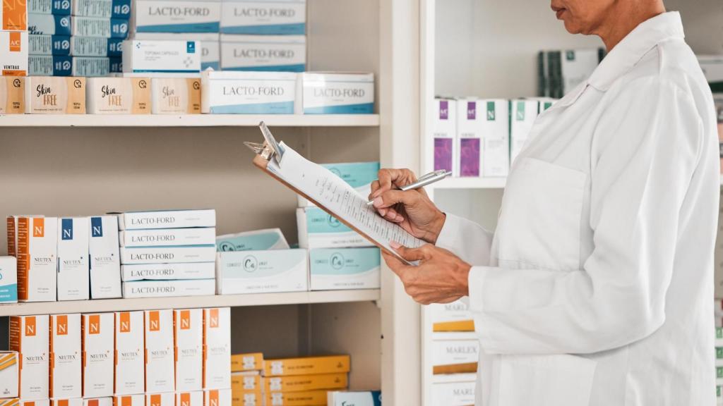 Mujer farmacéutica frente al stand de medicamentos.