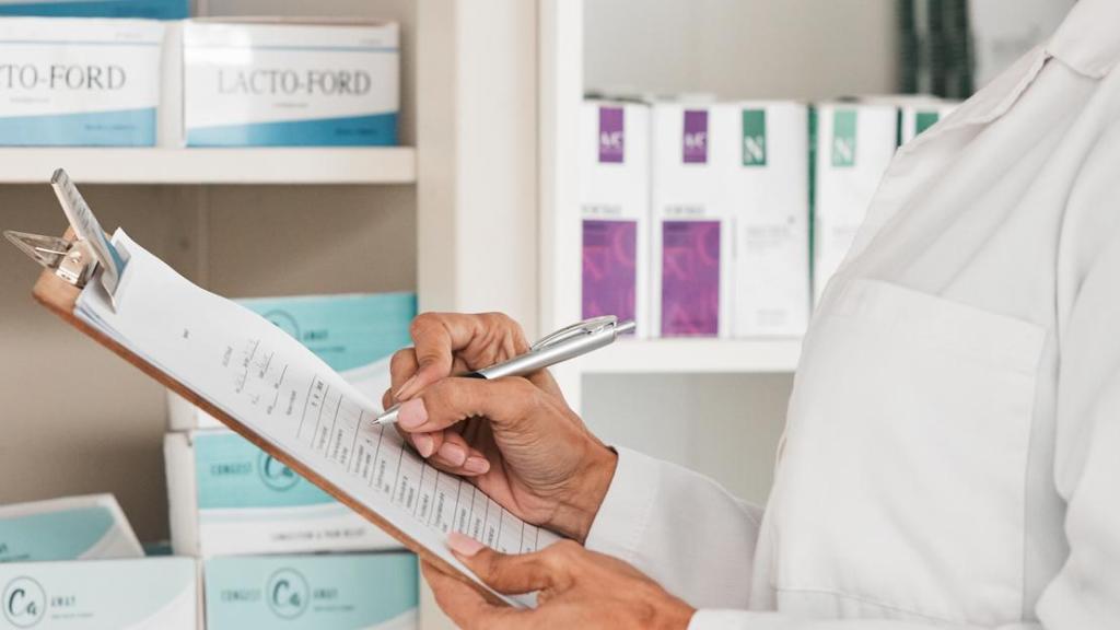 Una farmacéutica frente al stand de medicamentos.