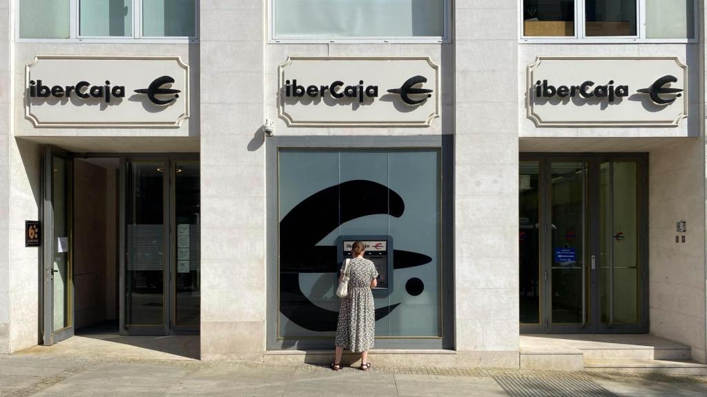 Una mujer saca dinero de una oficina de Ibercaja en Madrid.