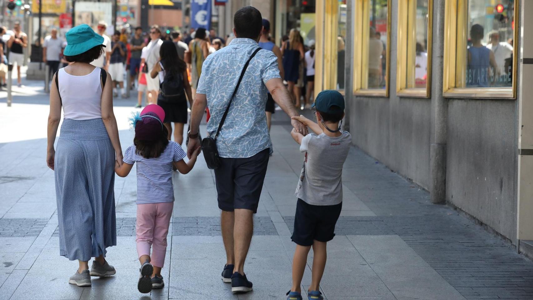 Una familia pasea de la mano por una calle de Madrid.