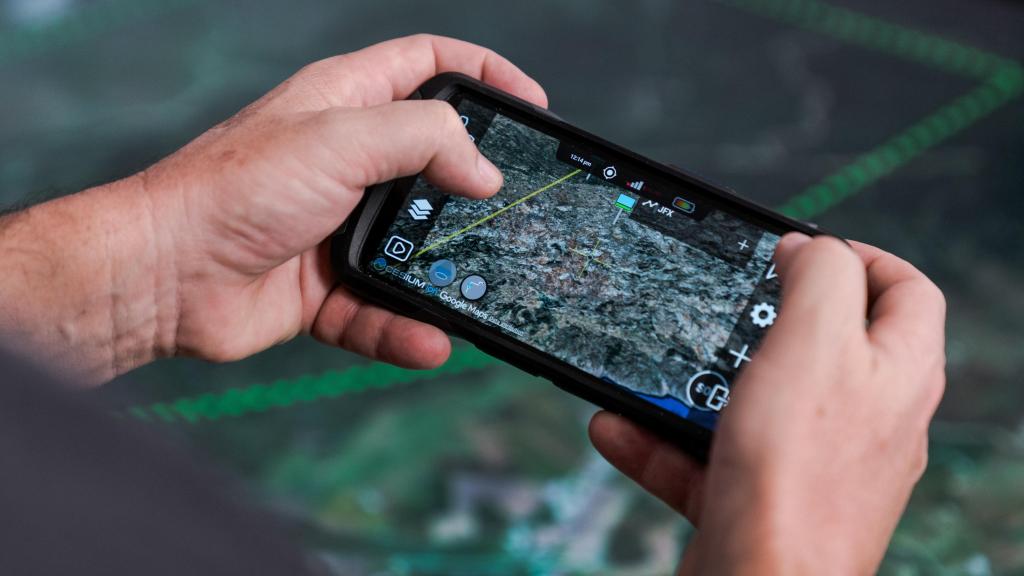 Detalle de un teléfono móvil con el sistema Apolo integrado; de fondo, la mesa Colossus.