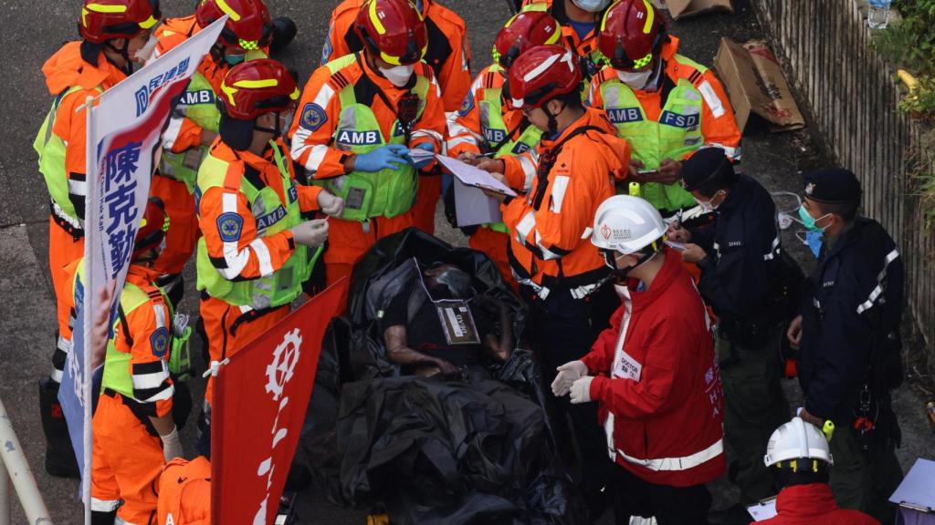 . Personal médico registra los detalles de un cuerpo recuperado del complejo residencial Wang Fuk Court.