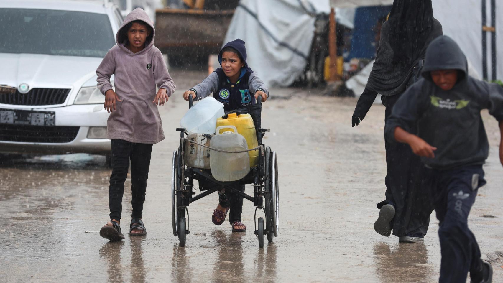 Unos niños buscan suministros durante un día de lluvia en Jan Yunis, Gaza.