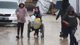 Unos niños buscan suministros durante un día de lluvia en Jan Yunis, Gaza.