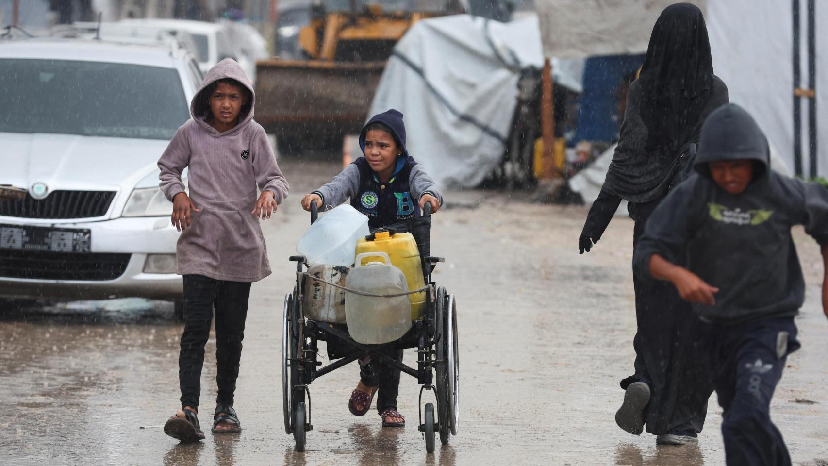 Unos niños buscan suministros durante un día de lluvia en Jan Yunis, Gaza.