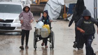 Unos niños buscan suministros durante un día de lluvia en Jan Yunis, Gaza.