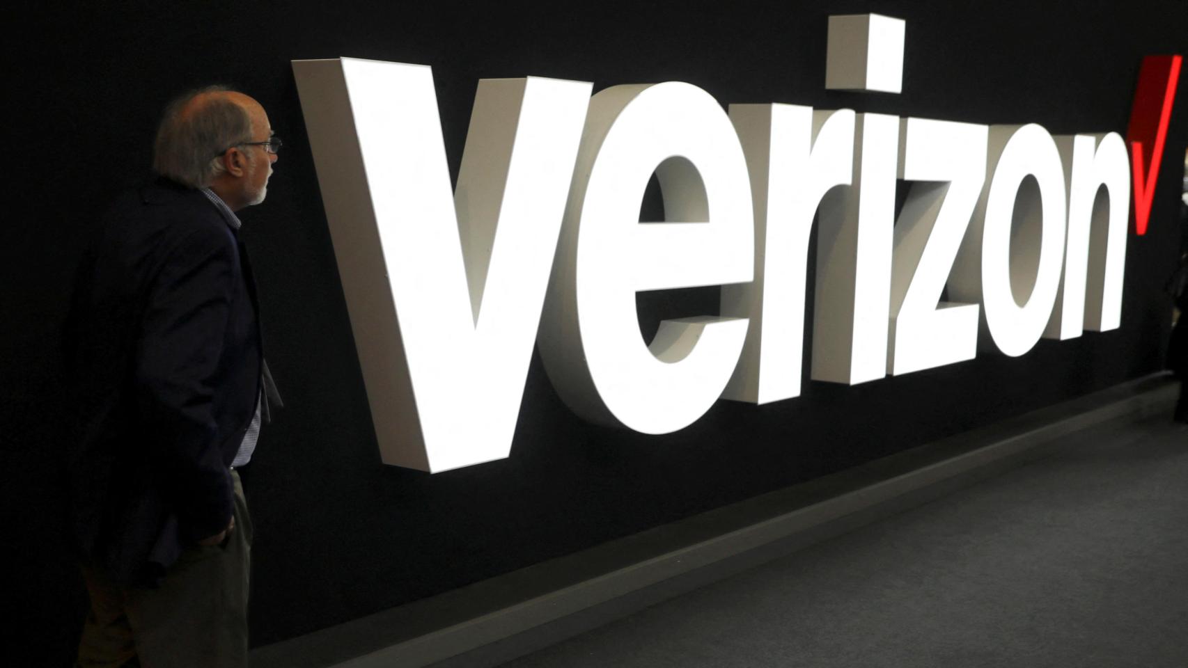 Un hombre delante del logo de Verizon.