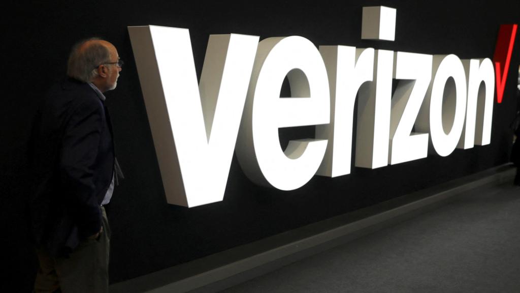 Un hombre delante del logo de Verizon.