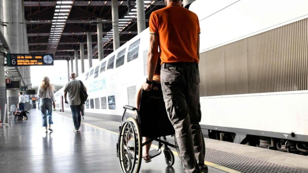 Un viajero en silla de ruedas, atendido por un auxiliar.