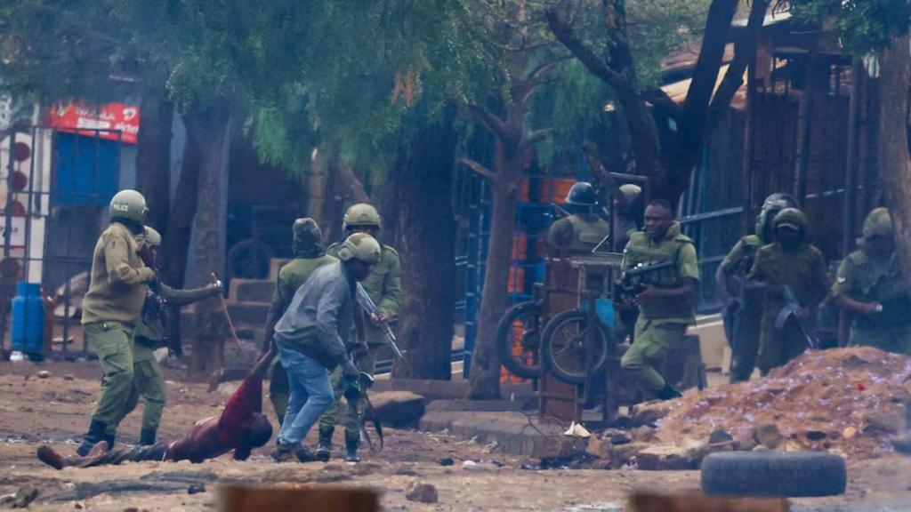 Policiais tanzanianos com o corpo sem vida de um homem durante protestos.