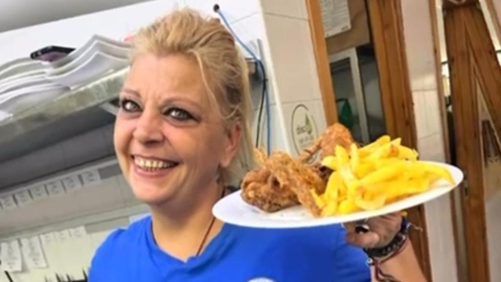 Una camarera, con un plato del menú.