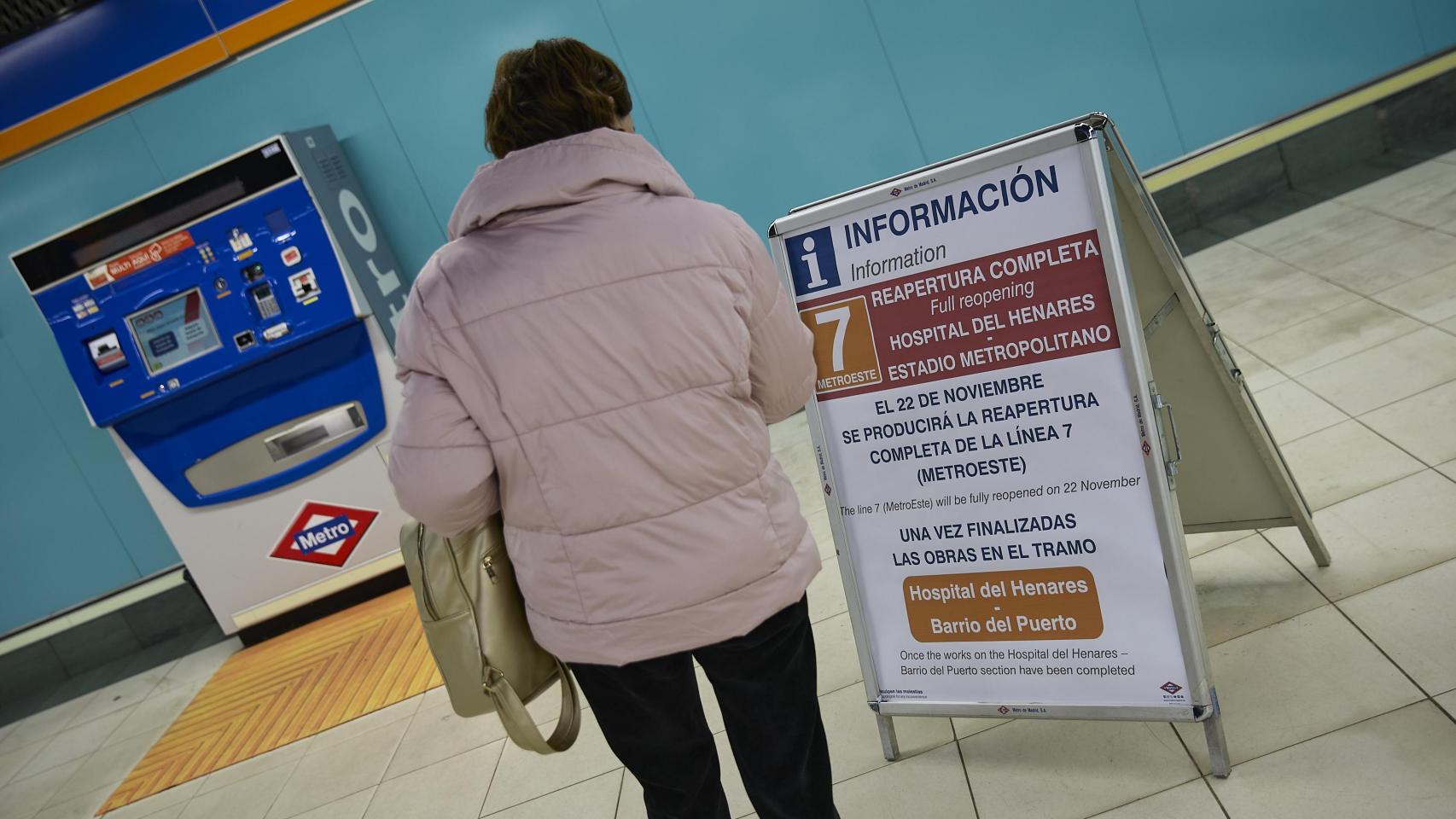 Una mujer frente a un cartel informativo del Metro de Madrid.