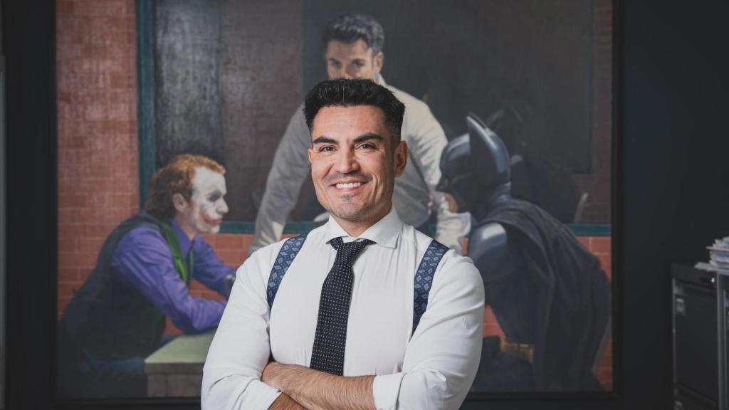 Alfredo Arrién, junto al cuadro que lo autorretrata como mediador entre el Joker y Batman.