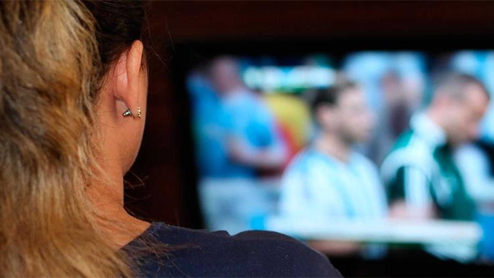 Espectadora viendo un partido de fútbol en televisión.