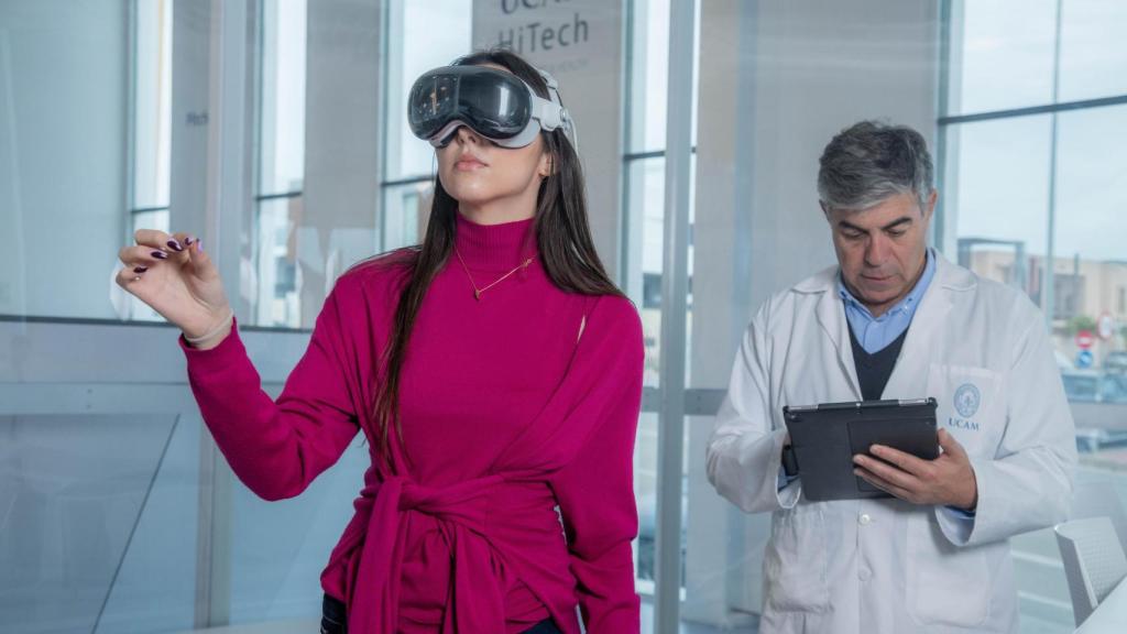 Una estudiante usando gafas de realidad virtual acompañada de un tutor.