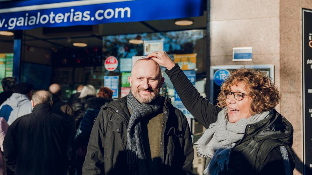 Imagen de Raúl y una mujer frotando su décimo con su calva.