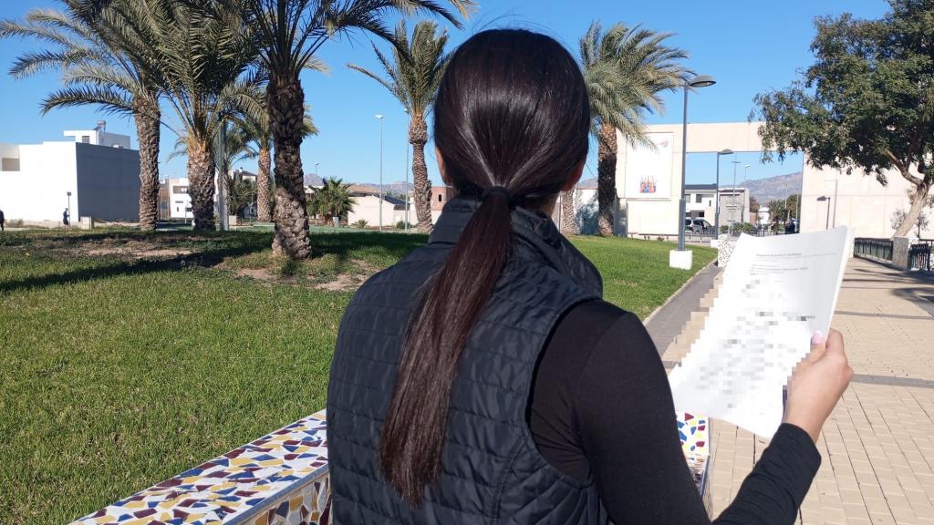 Fátima, nombre falso, este domingo, en el parque de un pueblo de Alicante, mostrando la denuncia contra su tío.