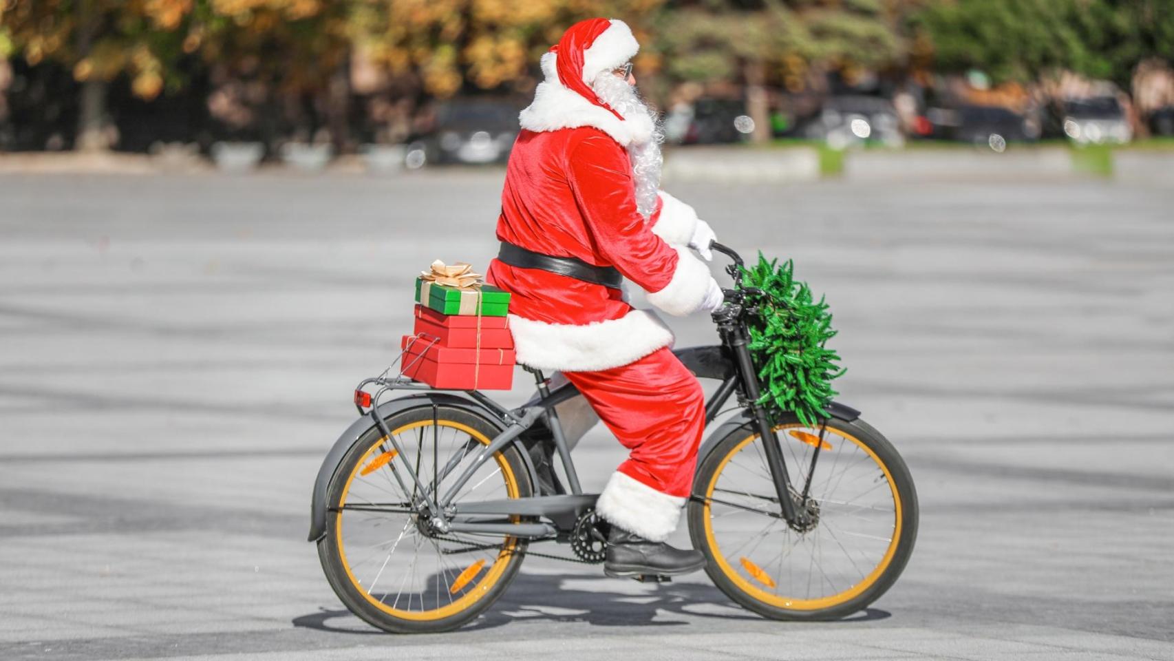 Una persona disfrazada de Papá Noel pasea en bicicleta