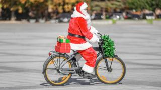 Una persona disfrazada de Papá Noel pasea en bicicleta