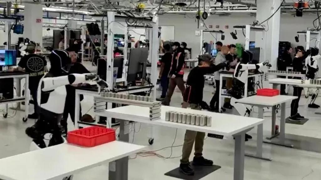 Imagen de un operario entrenando a un Optimus con un dispositivo de RV.