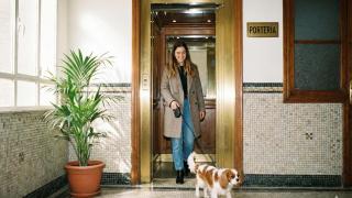 Mujer saliendo del ascensor con su perro.