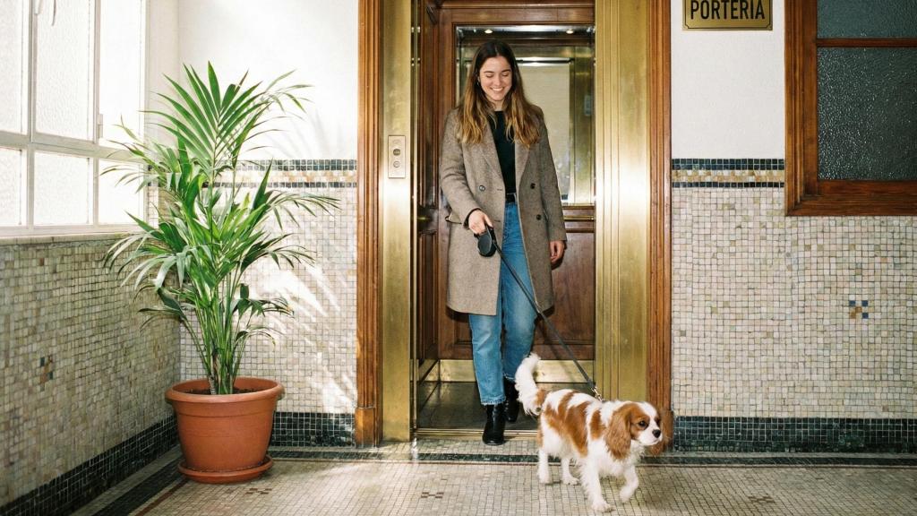Mujer saliendo del ascensor con su perro.