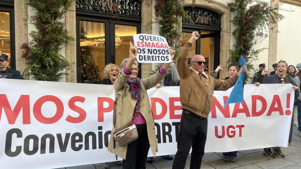 Dos manifestantes delante de la pancarta principal.