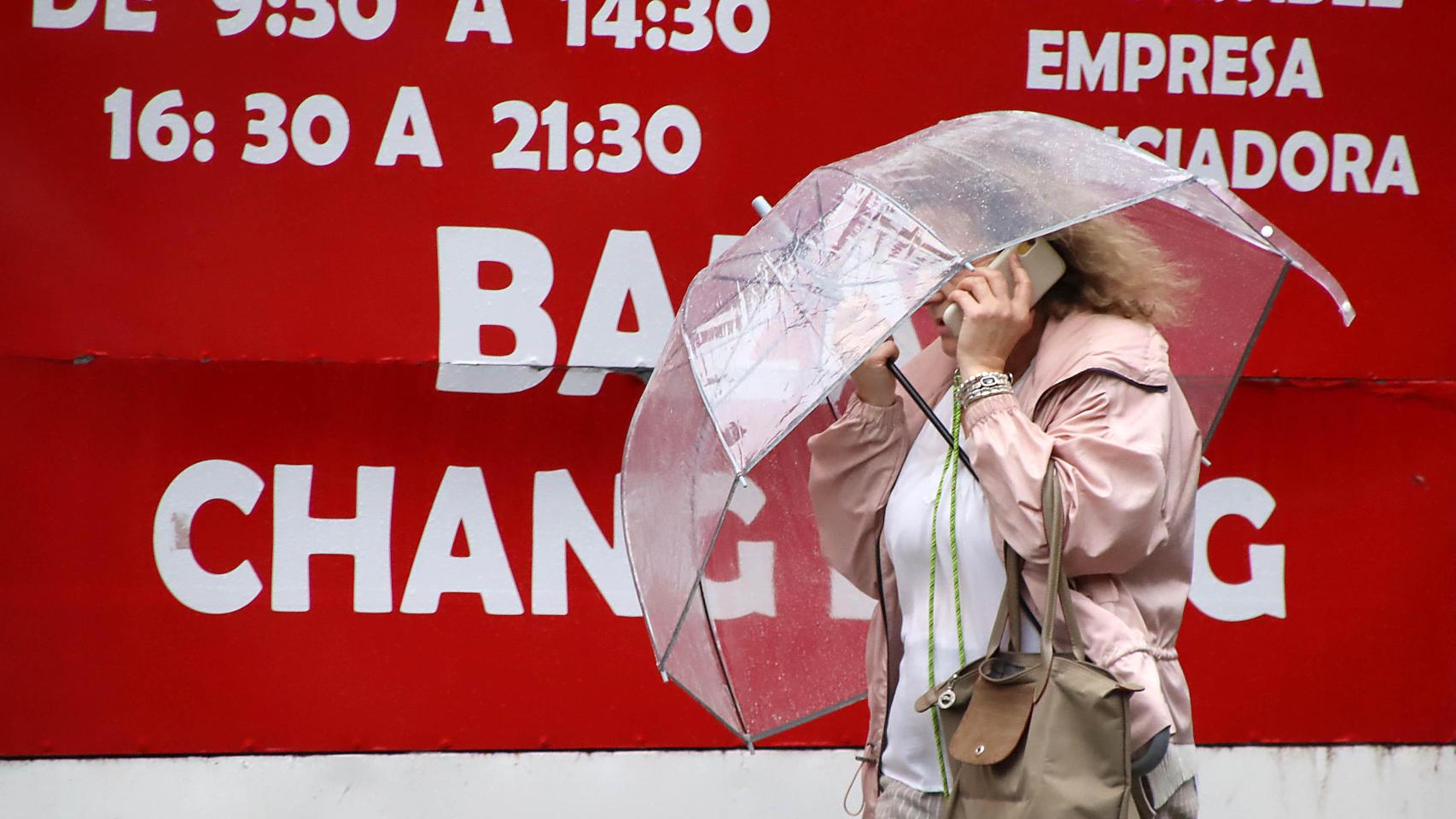 Una mujer se protege de la lluvia en León