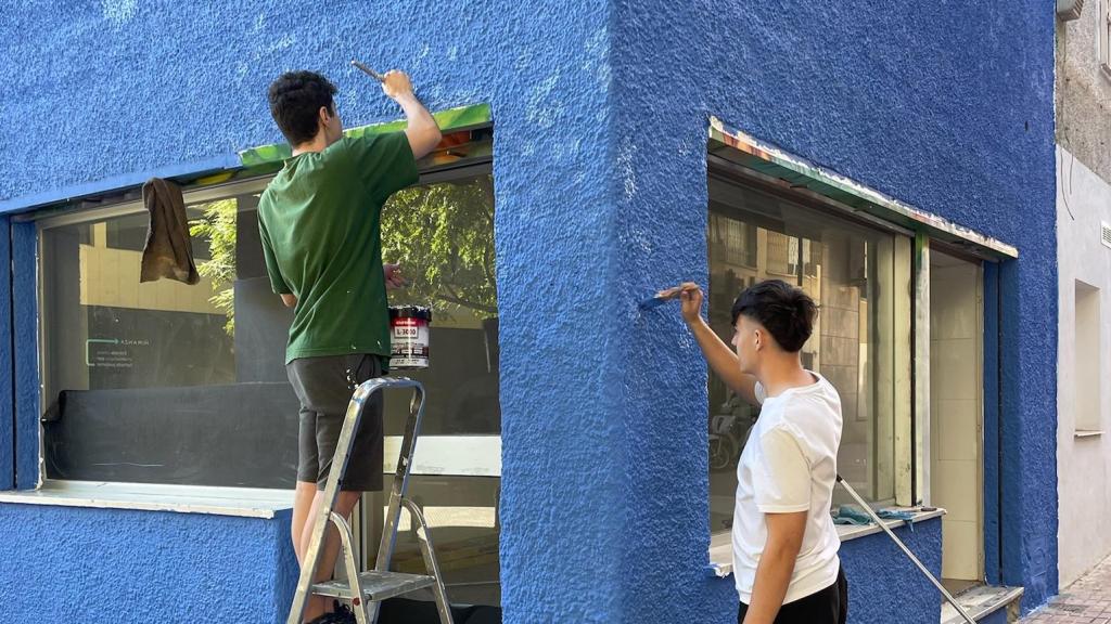 Iván y José pintando la fachada del local.