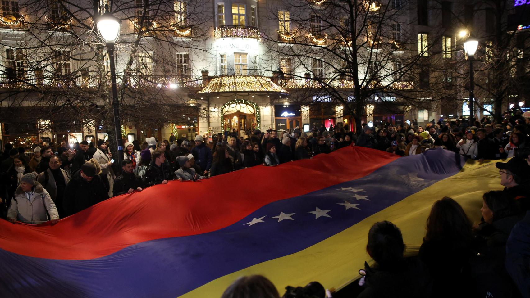 La gente sostiene una gran bandera nacional de Venezuela durante una procesión de antorchas para honrar a María Corina Machado, en Oslo, Noruega, el 10 de diciembre de 2025.