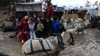 Palestinos se desplazan en carros tirados por animales por una calle inundada tras las fuertes lluvias del jueves en Jan Yunis.