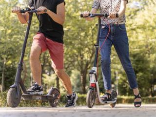 Imagen de archivo de dos personas usando patinetes eléctricos.