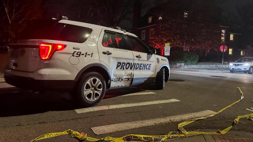 Un coche de policía pasa junto a una cinta policial tendida en la calle tras un tiroteo en la Universidad de Brown, en Providence.