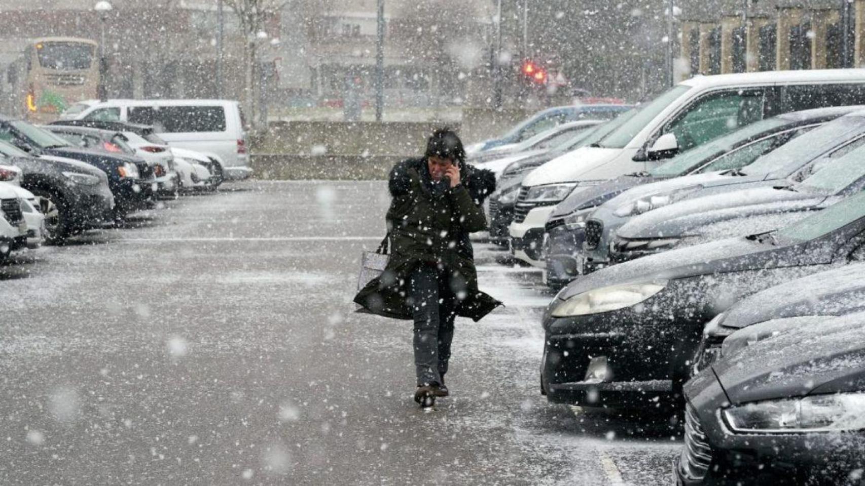 Imagen de archivo de una mujer bajo la nieve en Madrid.