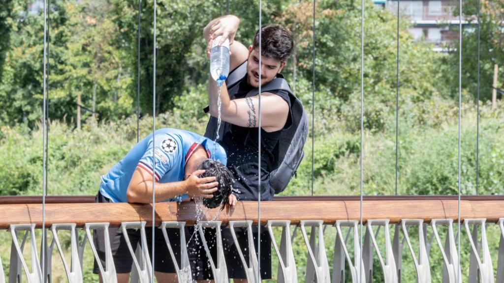 Un joven refresca a otro en plena ola de calor el 12 de agosto de 2025 en Madrid.